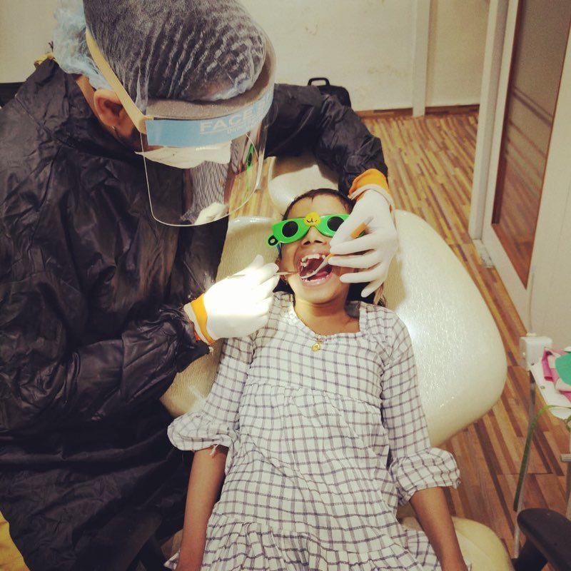Dr. Arjav Beswal examining a smiling young patient in the treatment chair